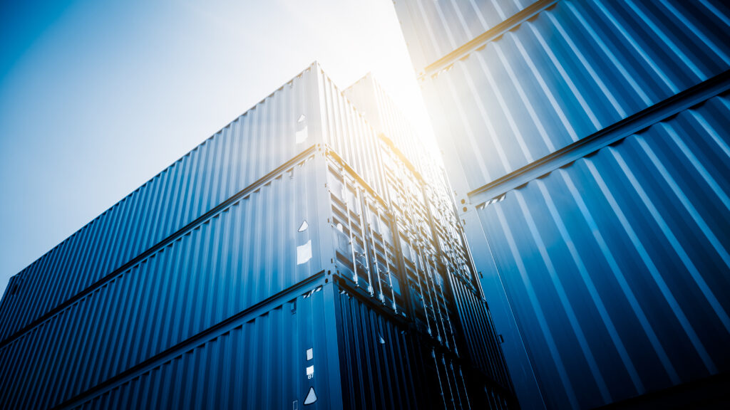 Shipping containers are arranged, showcasing vibrant colors against a backdrop of buildings.